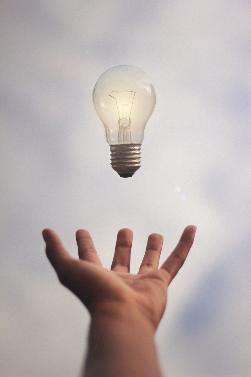 Hand reaching for a lightbulb — creative thinking and innovation